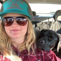 Reed Emily Reed smiles at the camera in a selfie from her car. Her pup leans their head on her shoulder.
