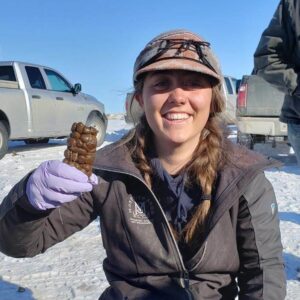 Brittany smiles at the camera, gleefully showing off a cylinder of ungulate poop.